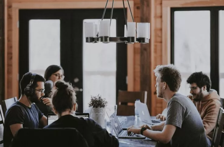 A group of people are sitting around a table, exchanging ideas and actively discussing.