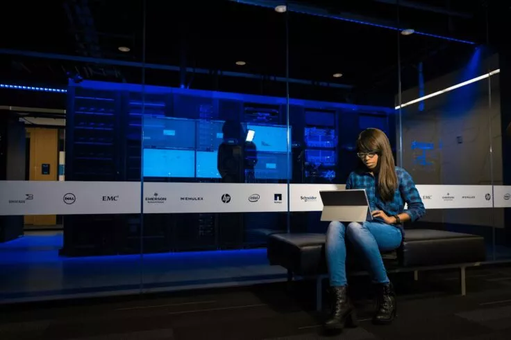 A woman sits with her computer, concentrating on her work.