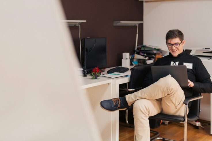 One person is sitting in a chair, concentrating on his laptop.