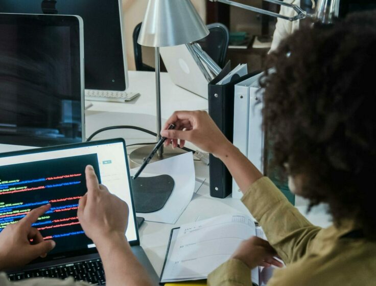 Two people in front of a computer, actively discussing their work.